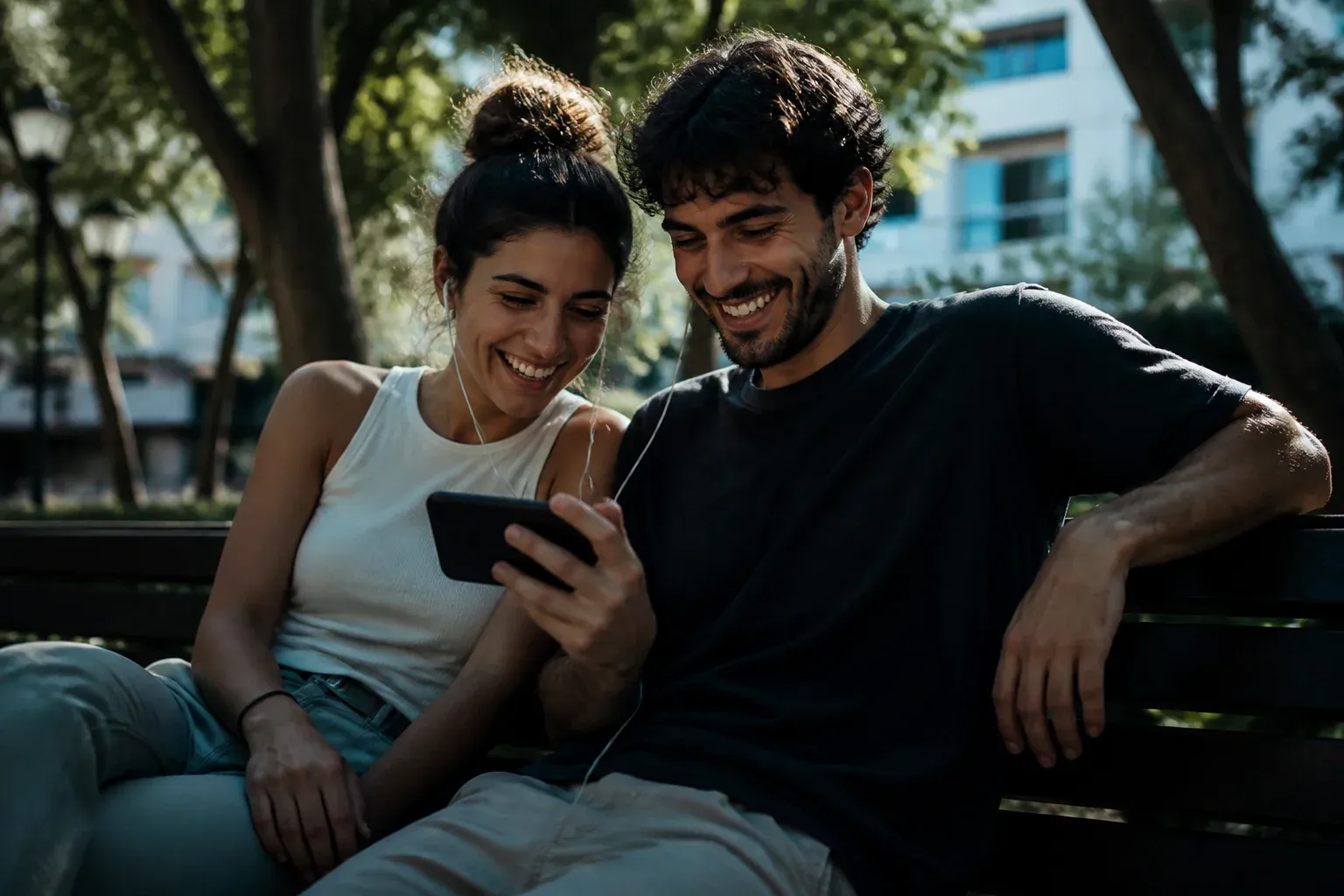 זוג צעירים צופה יחד בסרטון בטלפון על ספסל בפארק עירוני